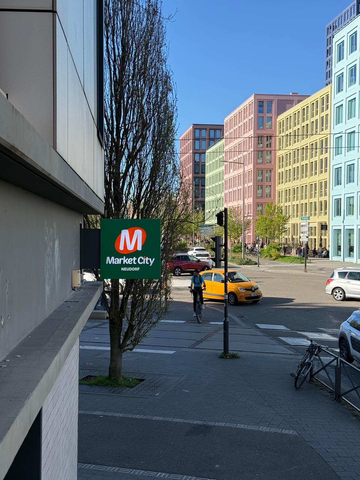 Conception, fabrication et installation de la vitrophanie d l&rsquo;enseigne drapeau et des enseignes lumineuses pour le secteur de la grande distribution chez Market City au Neudorf, proche d&rsquo;Illkirch-Graffenstaden.